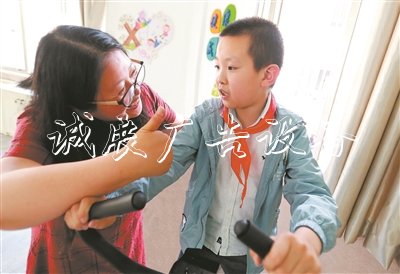 在无锡市广新小学融合教育资源中心,梁溪区特教指导中心资源教师陈向华指导小过进行康复训练,夸赞他有进步。