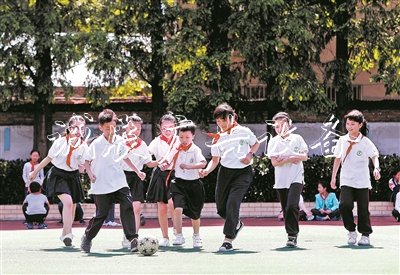 在无锡市广新小学操场上,随班就读学生小莹、小俊和同学们一起踢足球。阳光下,孩子们脸上绽放出灿烂的笑容。