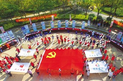2019年10月19日，上海开展“不忘初心、牢记使命”党员志愿者先锋行动，“两新”党员志愿者在公园广场托起一面党旗。  光明日报 图
