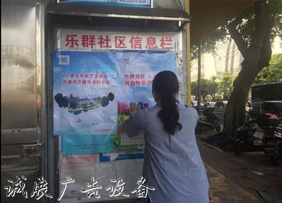 图为社区工作人员在宣传栏粘贴创城海报